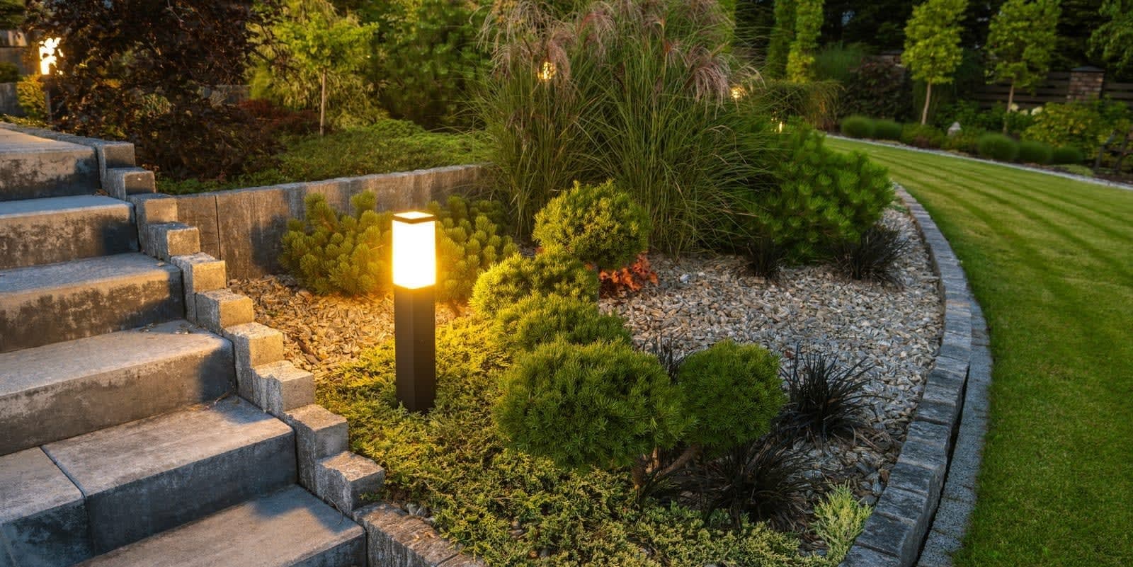Verlichte natuurstenen trap met plantvakken en sokkellamp